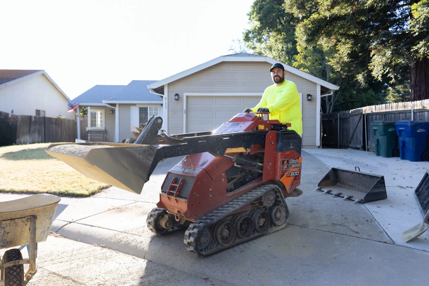 Cruz Landscaping and Design crew member with a skid steer on a driveway job site